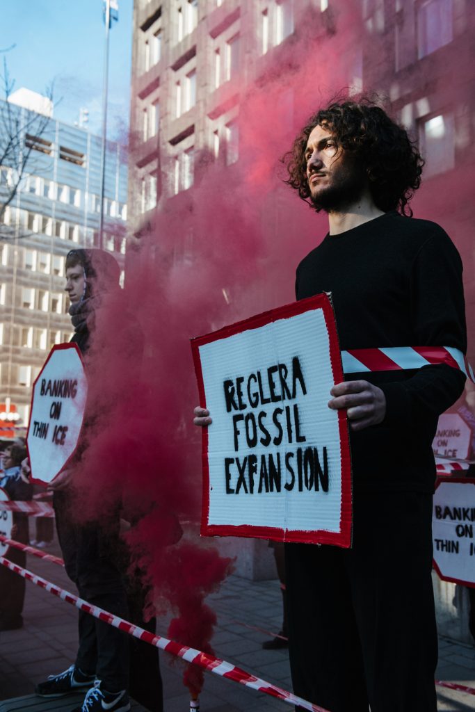 People stand with placards amid red smoke